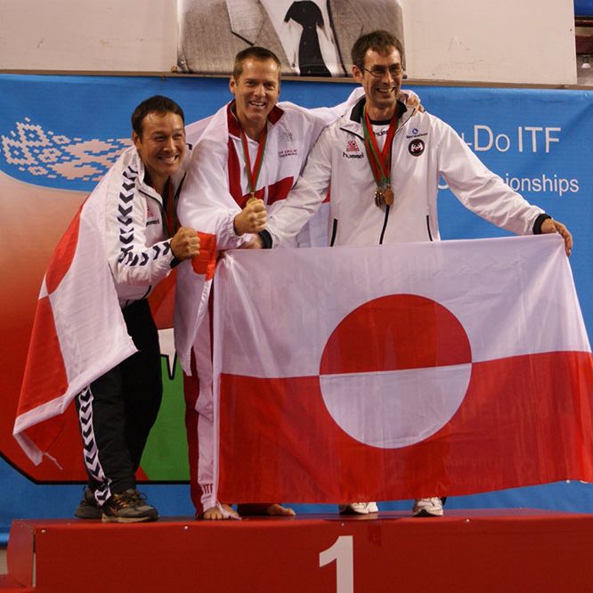 Surrey Taekwon-Do smiling men celebrating victory in a competition holding an iconic flag