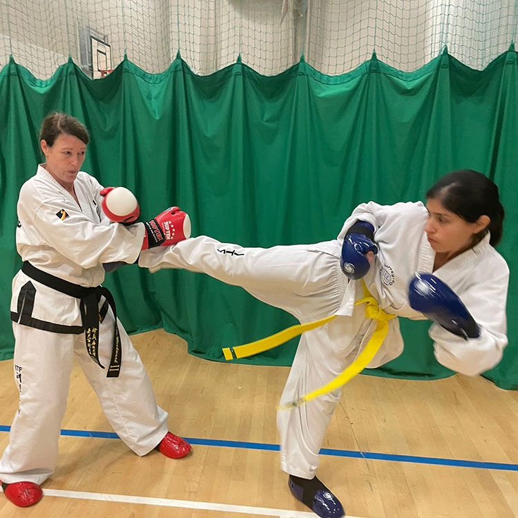 Surrey Taekwon-Do ladies performing a kick - one lady kicking, the other lady blocking