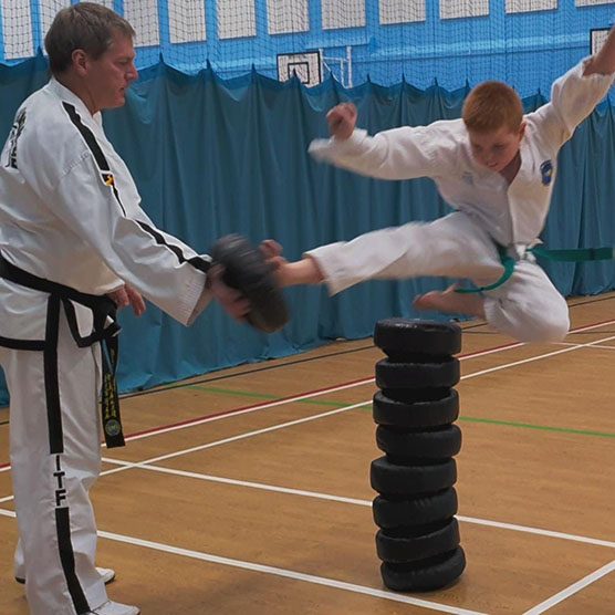 Surrey Taekwon-Do instructor in a gym with boy executing a flying kick move